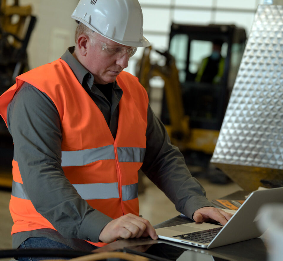 Man in construction gear using a laptop